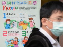 Homem se protege com máscara e cartaz dá orientações sobre a gripe. Foto: AFP/Sam Yeh 