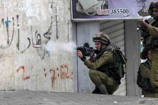 Soldado israelense atira bomba de efeito moral contra manifestantes palestinos no centro de Hebron, 29 de novembro, 2013, na Cisjordânia. Foto: Hazem Bader/ AFP Photo 